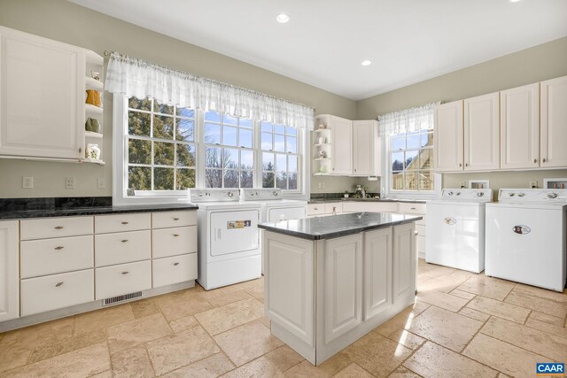 kitchen featuring open shelves, stone tile floors, and independent washer and dryer