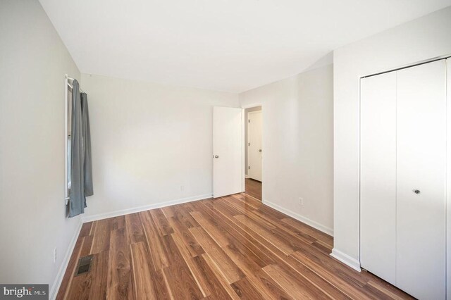 unfurnished bedroom with hardwood / wood-style flooring and a closet