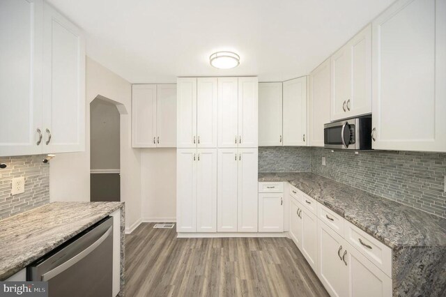 kitchen featuring light stone counters, hardwood / wood-style flooring, white cabinets, and appliances with stainless steel finishes