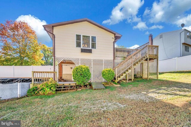 back of property with a wooden deck and a yard