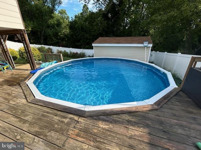 view of swimming pool featuring a storage shed and a deck