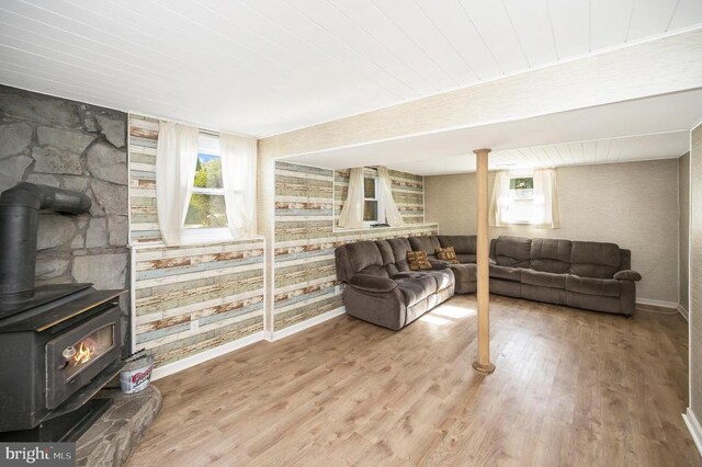 living room with light hardwood / wood-style floors, wooden ceiling, and a wood stove