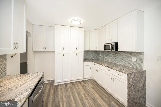 kitchen featuring light stone counters, appliances with stainless steel finishes, dark hardwood / wood-style flooring, decorative backsplash, and white cabinets