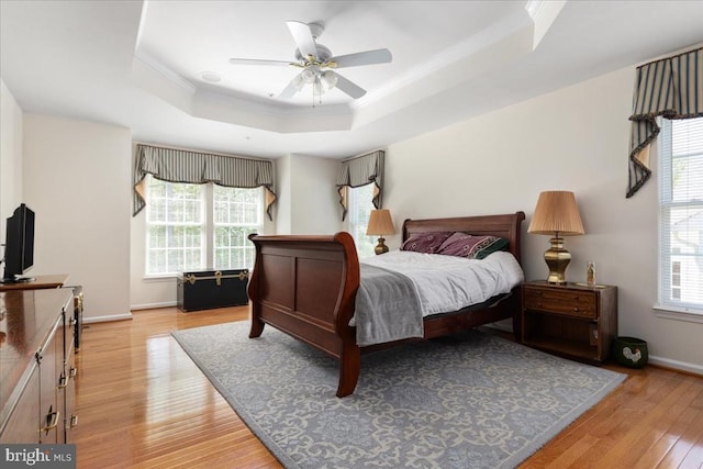  - bedroom with baseboards, a raised ceiling, ornamental molding, and light wood-style floors