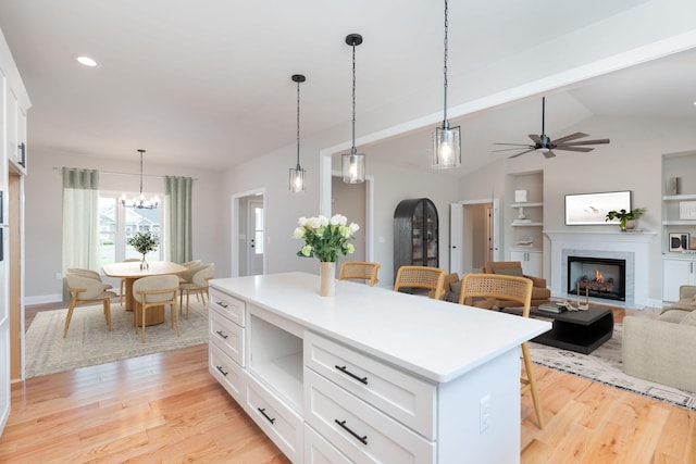 409 Peterson Ln, Waynesboro, VA 22980 - kitchen featuring light wood-style flooring, a kitchen bar, white cabinets, a fireplace, and vaulted ceiling