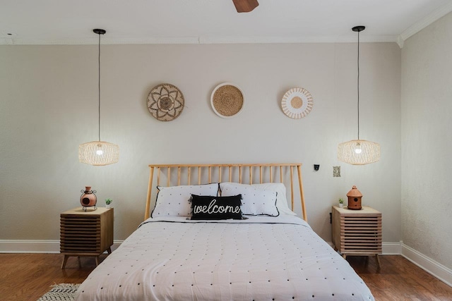 bedroom with wood finished floors, baseboards, and ornamental molding