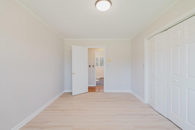 unfurnished bedroom with light wood-type flooring, crown molding, a closet, and baseboards