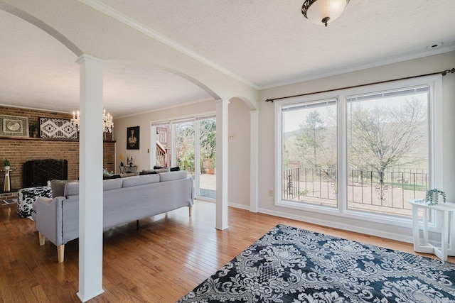 bedroom with arched walkways, ornate columns, a textured ceiling, wood-type flooring, and ornamental molding