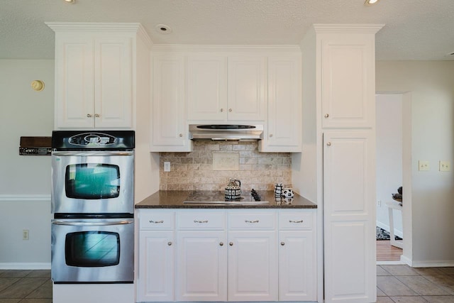 kitchen featuring black electric cooktop, stainless steel double oven, ventilation hood, tasteful backsplash, and white cabinets