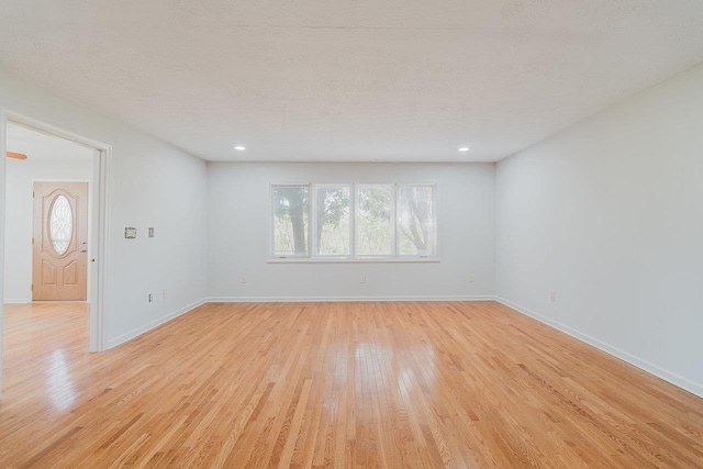 unfurnished living room featuring light wood-style floors, baseboards, a textured ceiling, and recessed lighting
