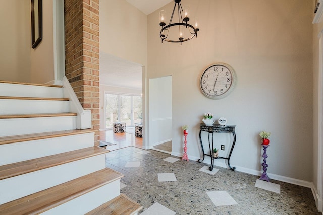 foyer with baseboards, a chandelier, stairway, and a towering ceiling