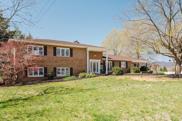 tri-level home featuring brick siding and a front yard
