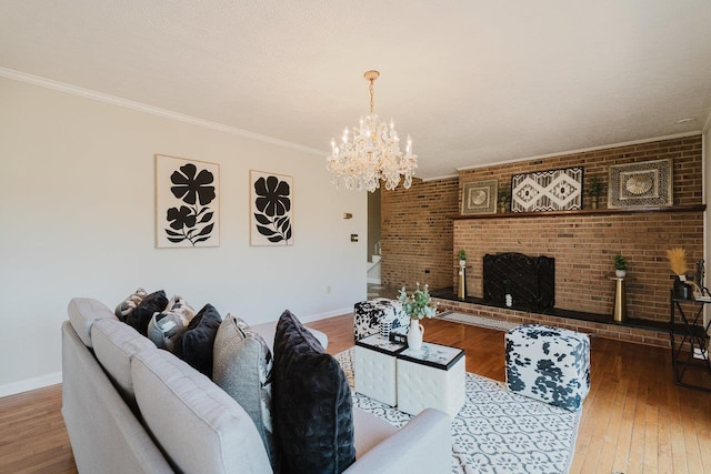 living area with a chandelier, wood-type flooring, baseboards, a fireplace, and ornamental molding