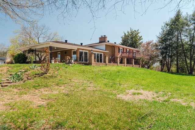 rear view of property with a chimney, a lawn, brick siding, and a deck