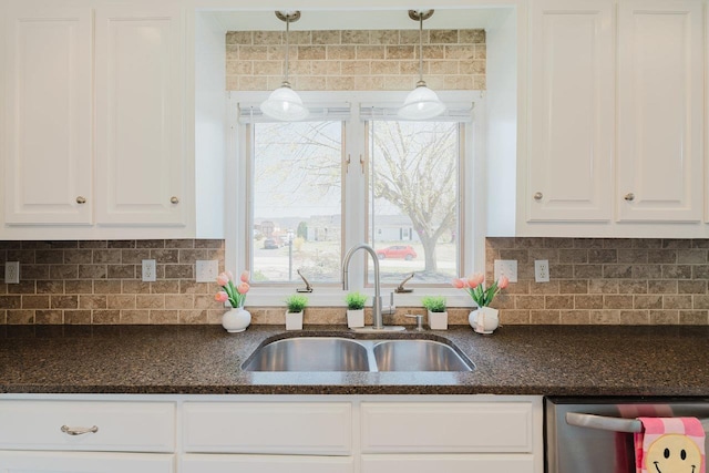 kitchen featuring a sink, stainless steel dishwasher, white cabinets, and dark stone counters