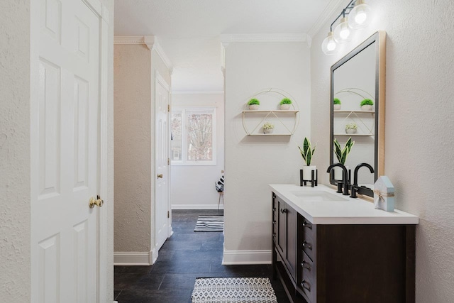bathroom featuring crown molding, vanity, a textured wall, and baseboards