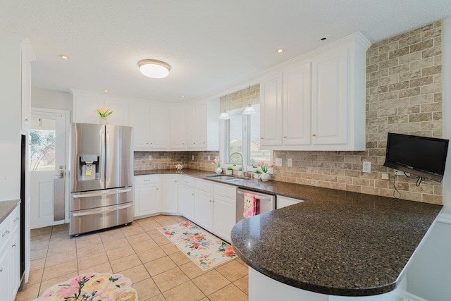 kitchen featuring appliances with stainless steel finishes, a sink, a peninsula, white cabinets, and a textured ceiling