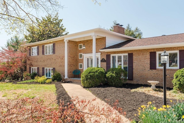 tri-level home with a chimney and brick siding