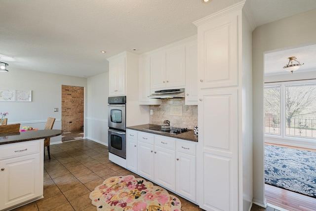 kitchen featuring dark countertops, white cabinetry, tasteful backsplash, a textured ceiling, and recessed lighting