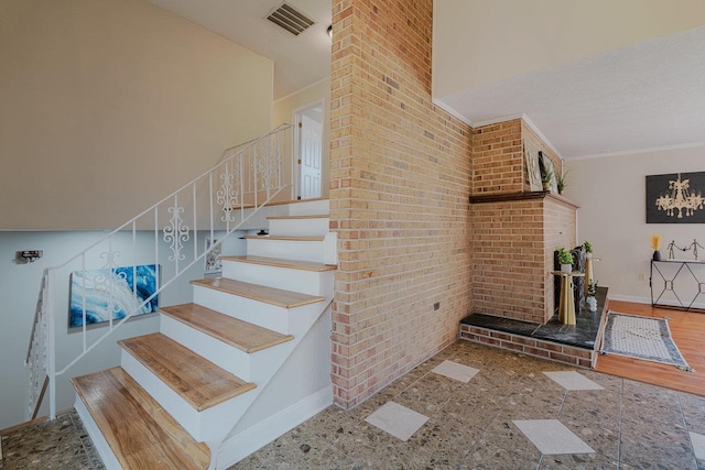 staircase featuring baseboards, ornamental molding, and brick wall
