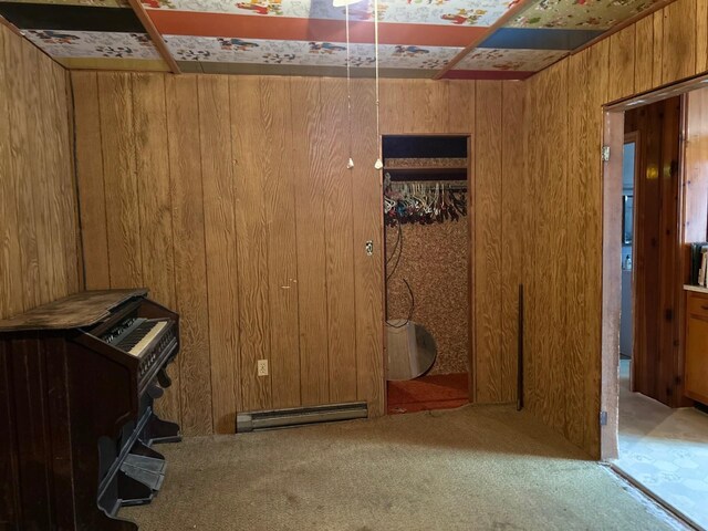 unfurnished bedroom with a baseboard radiator, wood walls, and carpet