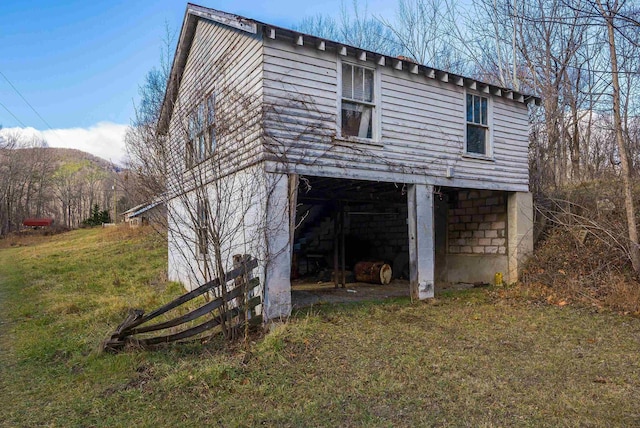 view of side of home with a mountain view and a lawn