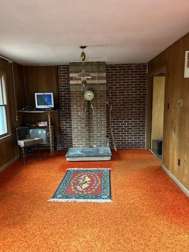 unfurnished living room with wood walls, carpet flooring, and baseboards