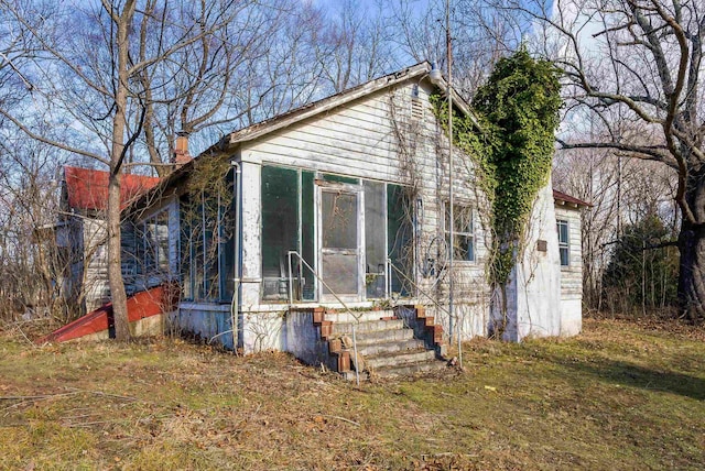 view of front facade featuring a sunroom and a chimney