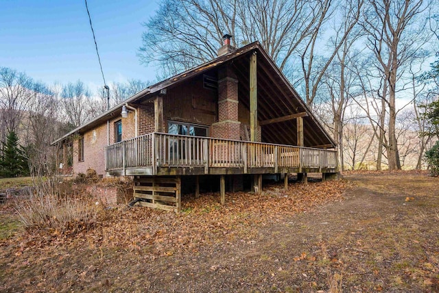 back of house featuring brick siding, a deck, and a chimney