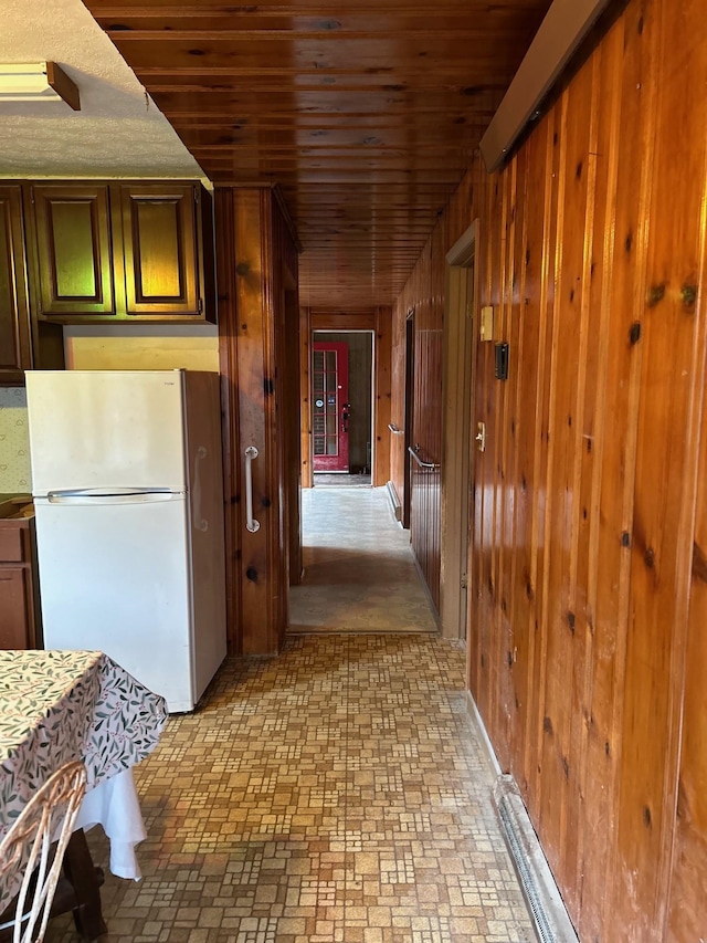 hallway featuring brick patterned flooring, wood walls, and wood ceiling