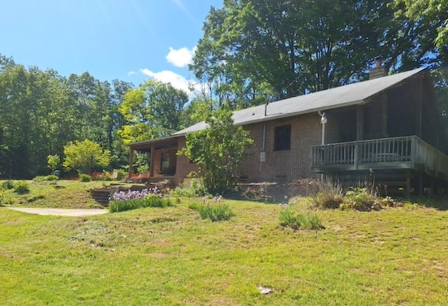 rear view of house featuring a lawn, brick siding, a wooden deck, and crawl space