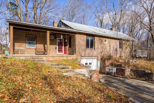 ranch-style house featuring a chimney, brick siding, and concrete driveway