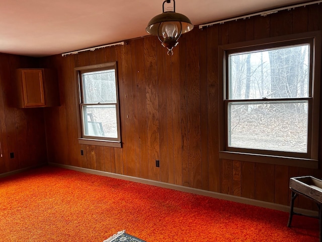 unfurnished room with light colored carpet and wood walls