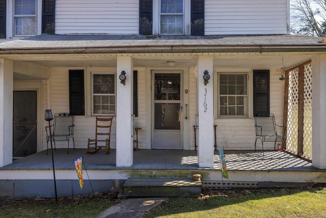 property entrance featuring roof with shingles and covered porch