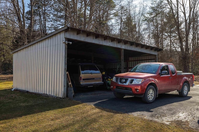 view of car parking featuring a detached carport, an outbuilding, and driveway