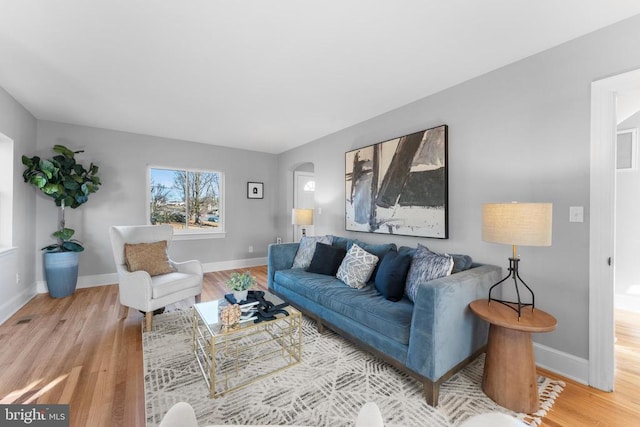 living area featuring baseboards, arched walkways, and wood finished floors