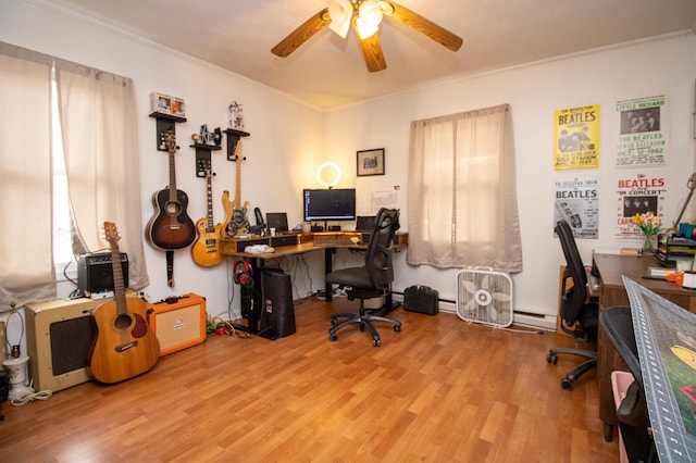 home office featuring a baseboard heating unit, ornamental molding, ceiling fan, and light wood-type flooring