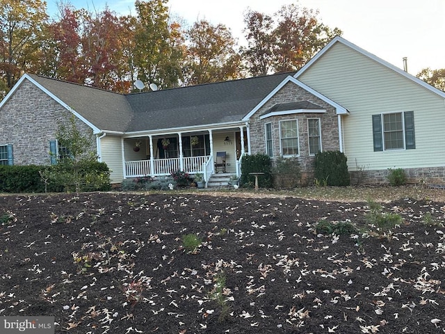single story home featuring a porch and stone siding
