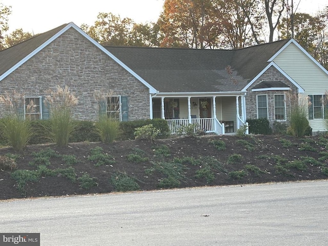 single story home featuring covered porch and stone siding