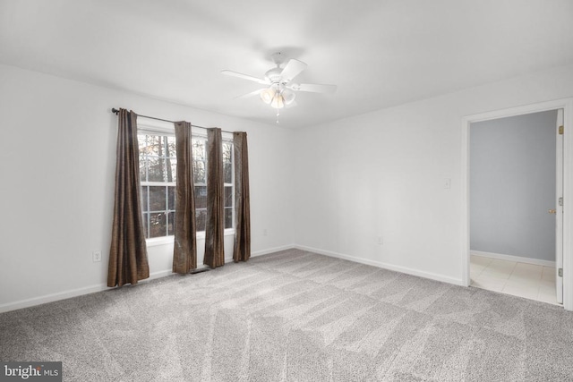 carpeted empty room featuring baseboards and ceiling fan