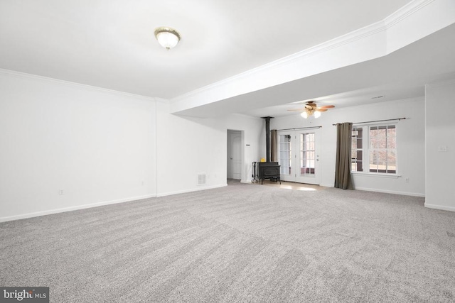 unfurnished living room featuring crown molding, a wood stove, and carpet floors