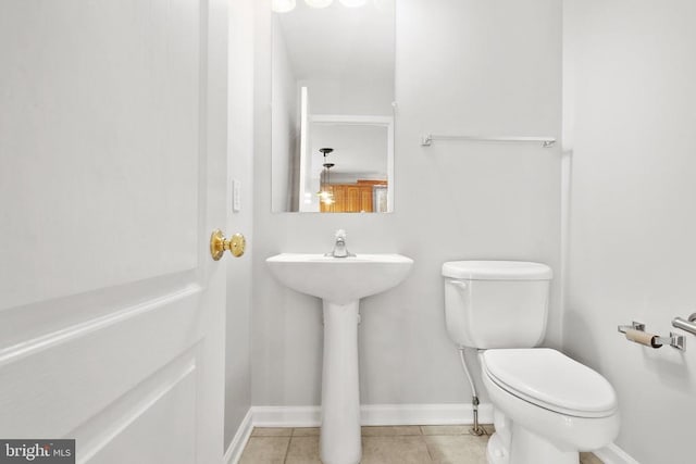 half bath featuring toilet, tile patterned floors, and baseboards