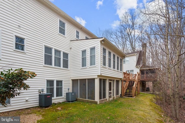 back of house featuring cooling unit, a yard, stairway, and a sunroom