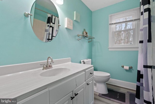 full bath with toilet, curtained shower, wood finished floors, baseboards, and vanity