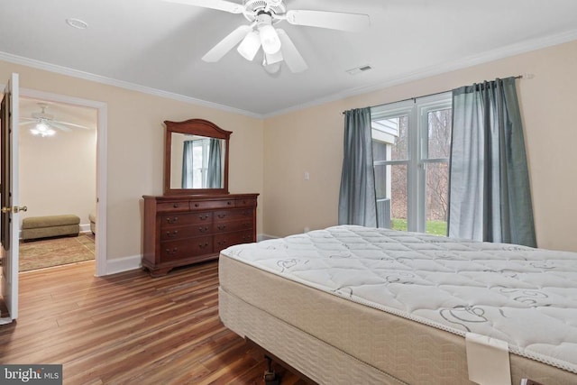 bedroom with visible vents, baseboards, wood finished floors, and crown molding