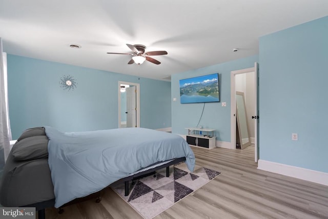 bedroom featuring light wood finished floors, visible vents, a ceiling fan, and baseboards