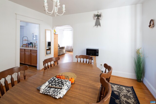 dining space with hardwood / wood-style flooring and a notable chandelier