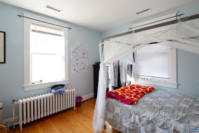 bedroom featuring radiator heating unit and light hardwood / wood-style floors