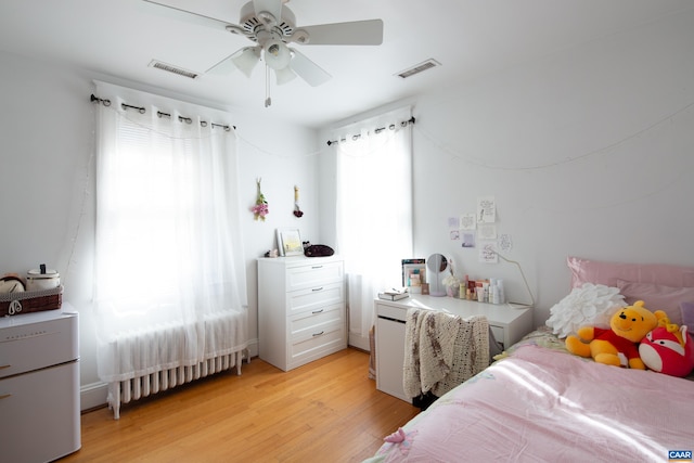 bedroom with ceiling fan, radiator, and light hardwood / wood-style floors