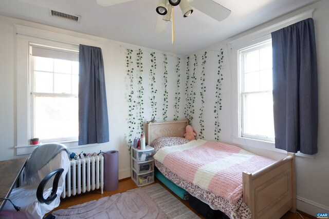 bedroom featuring wood-type flooring, radiator, and ceiling fan